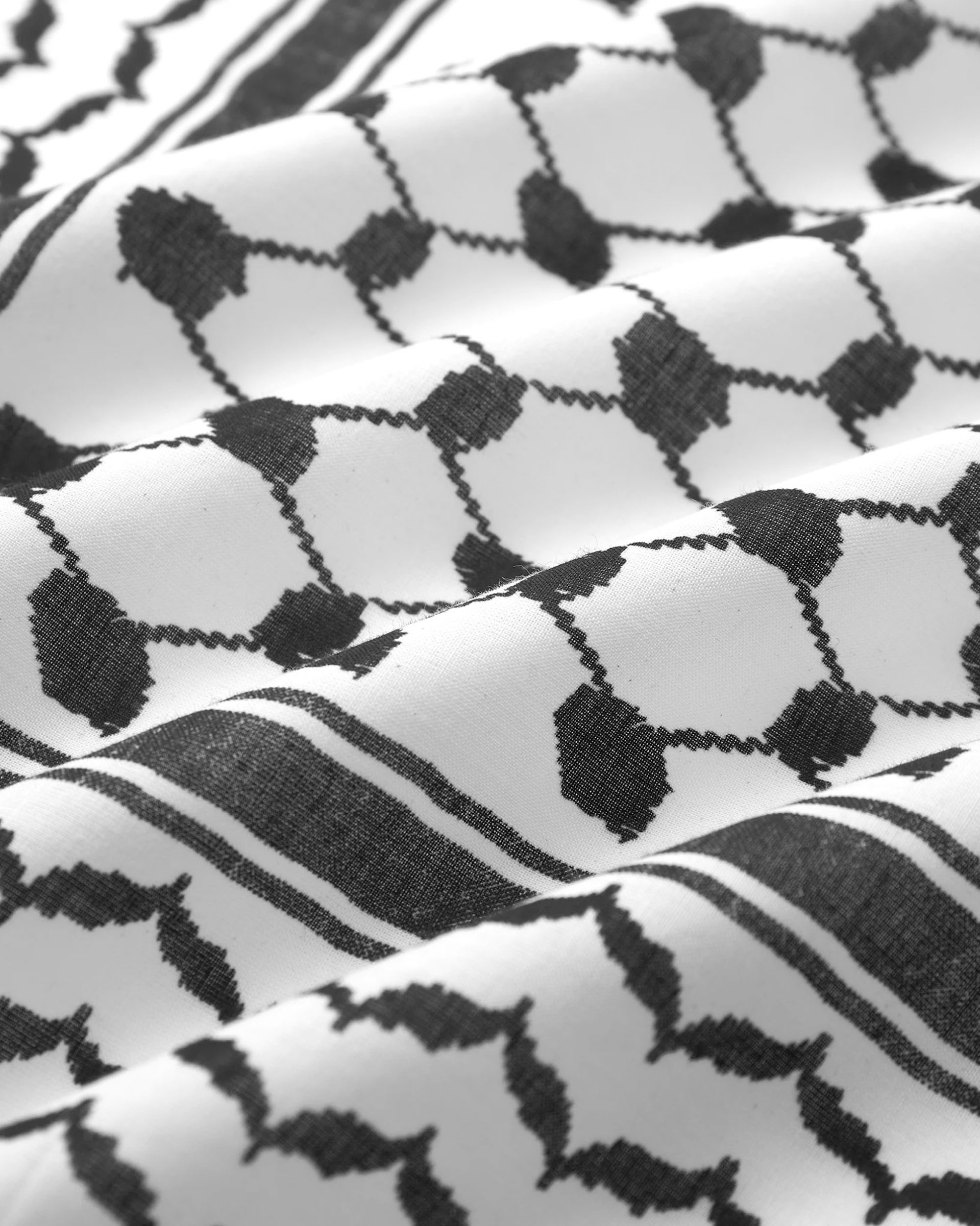 A black and white patterned design on white fabric, featuring traditional geometric shapes and lines.