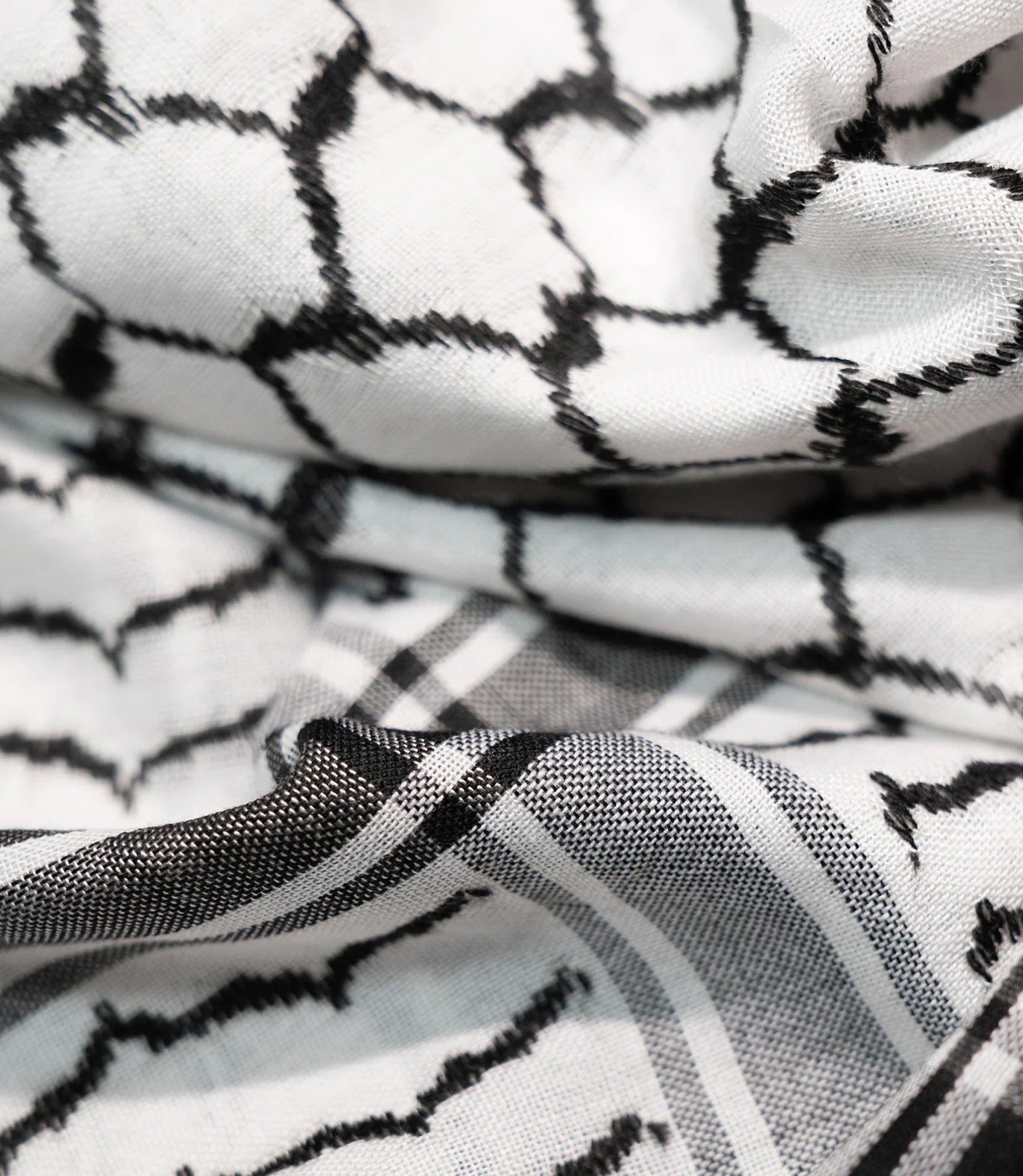 A black and white patterned design on white fabric, featuring traditional geometric shapes and lines.